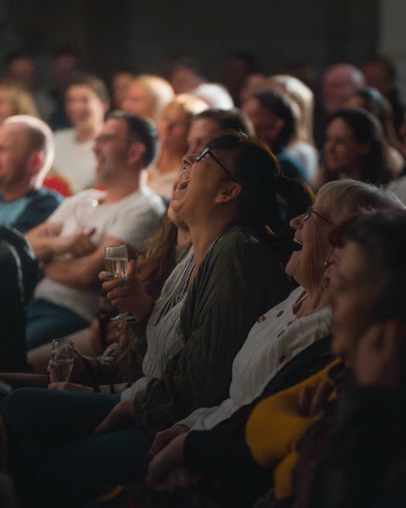 Audience members laughing at a live comedy show.